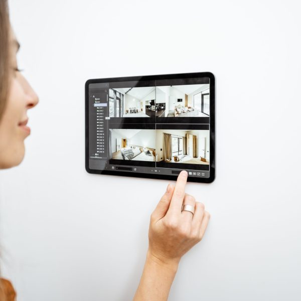 Young woman watching video from security cameras on a digital tablet at home. Concept of remote video surveillance over the internet with smart devices